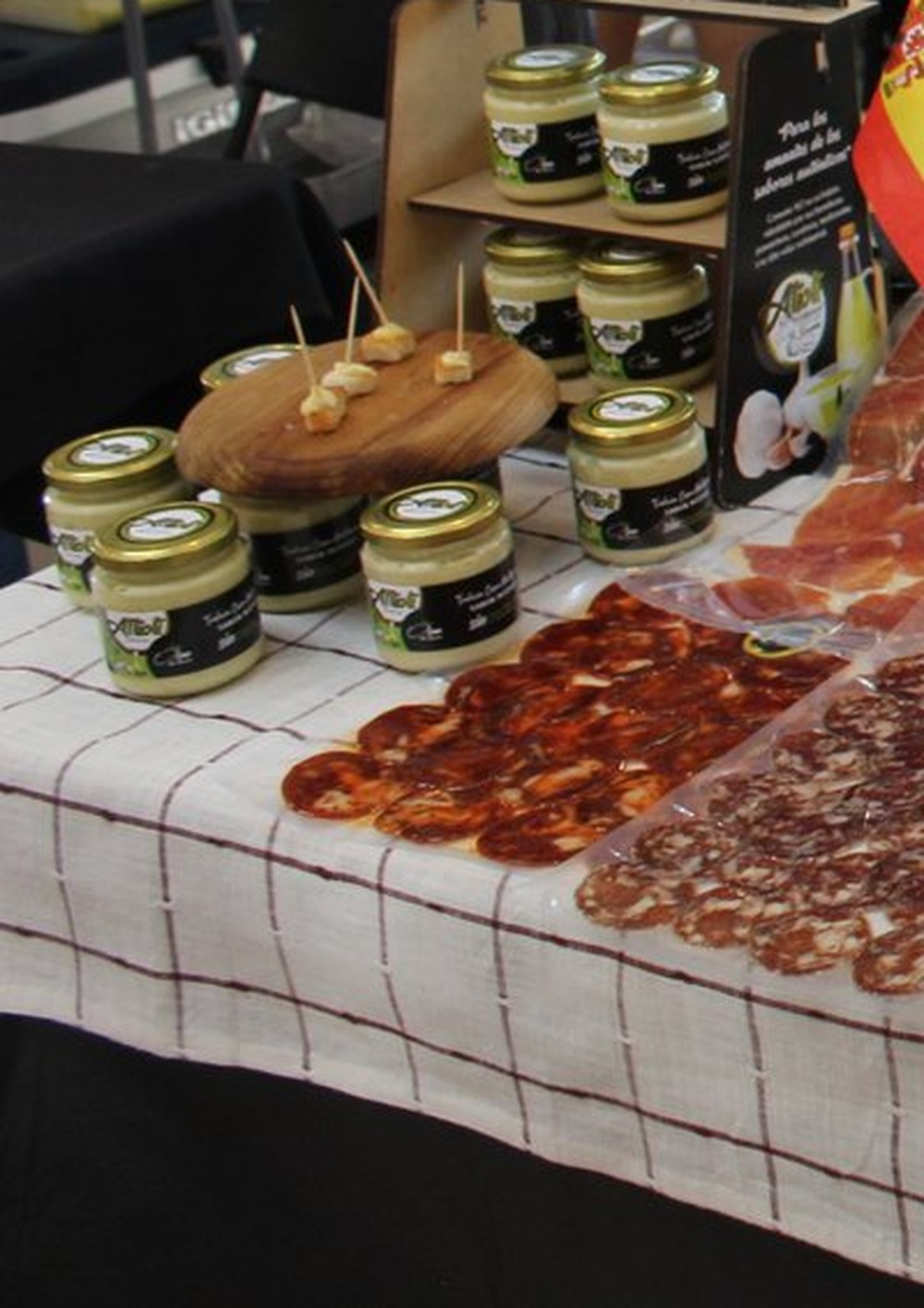 Frascos de alioli artesanal de Ferrán, junto a jamón serrano y embutidos en rebanadas finas