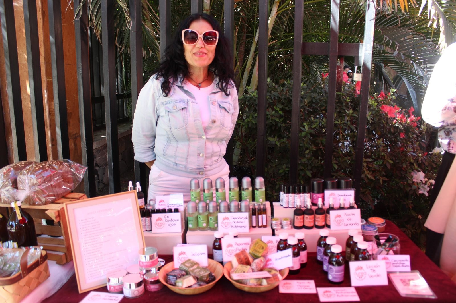 Alicia Barajas en el puesto de Aurea Herbolaria, con jabones, aceites y desodorantes exhibidos en frascos de vidrio