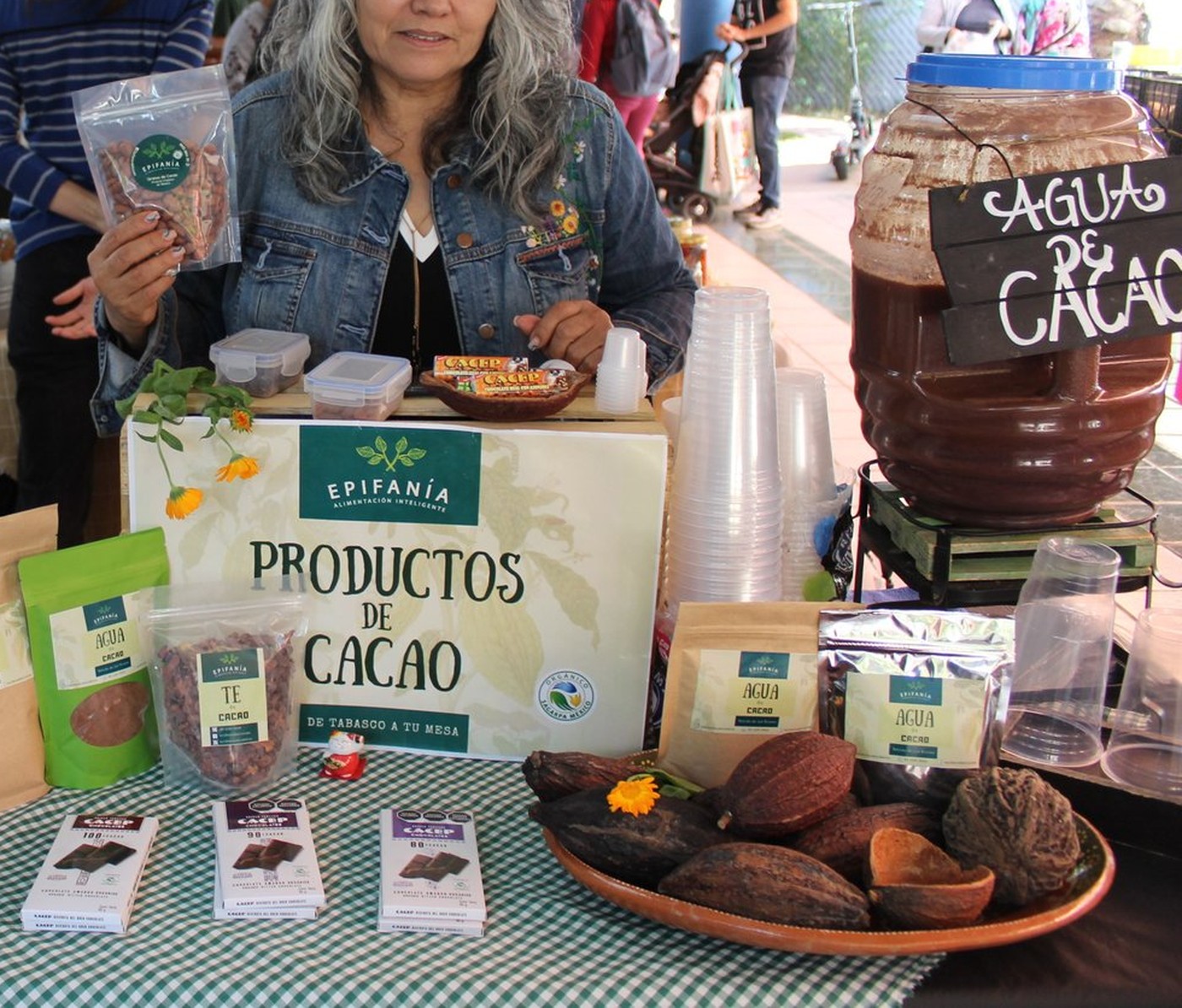Productora de Epifanía con el letrero 'Productos de Cacao, de Tabasco a tu mesa', frascos de agua de cacao, té de cacao y tabletas de chocolate