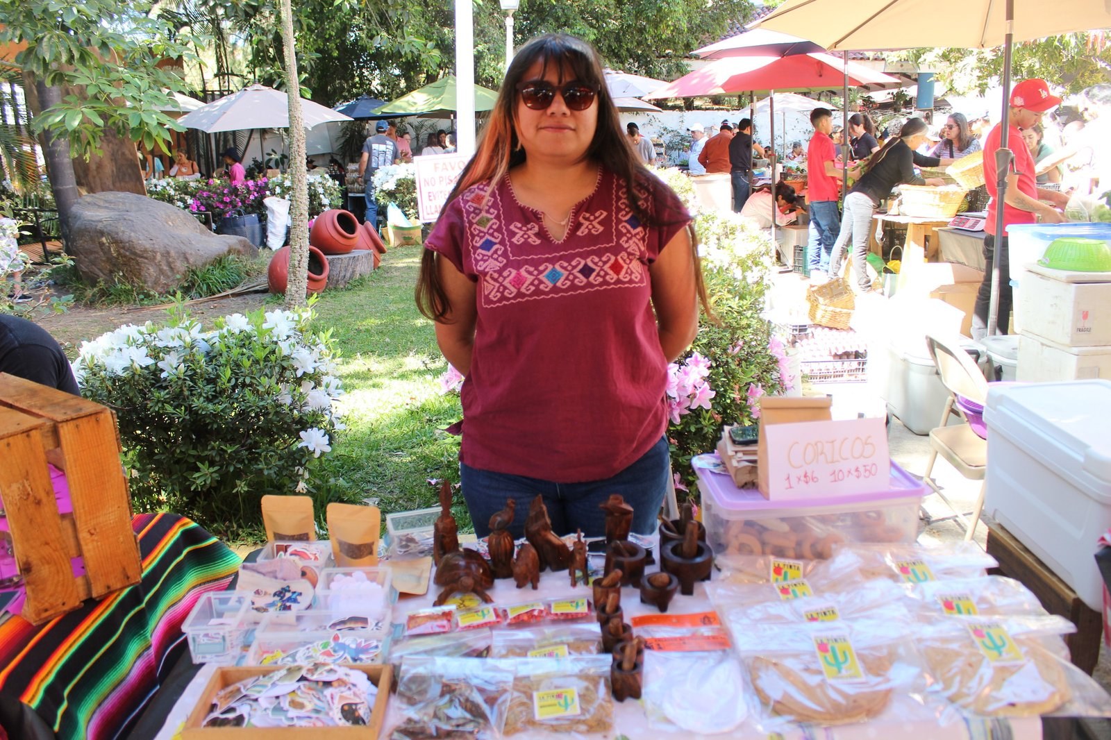 Ana Jeniffer Sánchez Villafaña en su puesto, con coricos, artesanías de palo fierro y paquetes de tortillas
