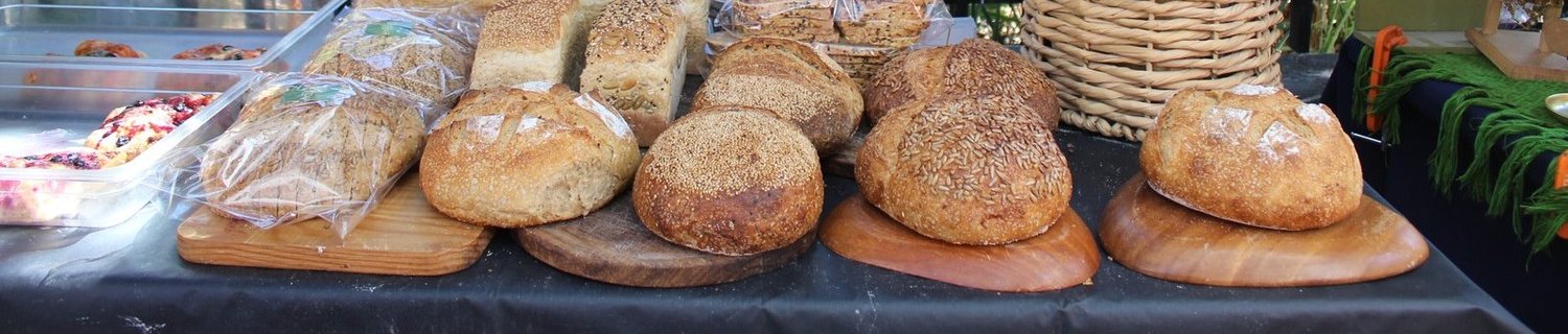 Hogazas de pan de masa madre con costra de ajonjolí y semillas, y baguettes en canasta de mimbre, de Lúcuma