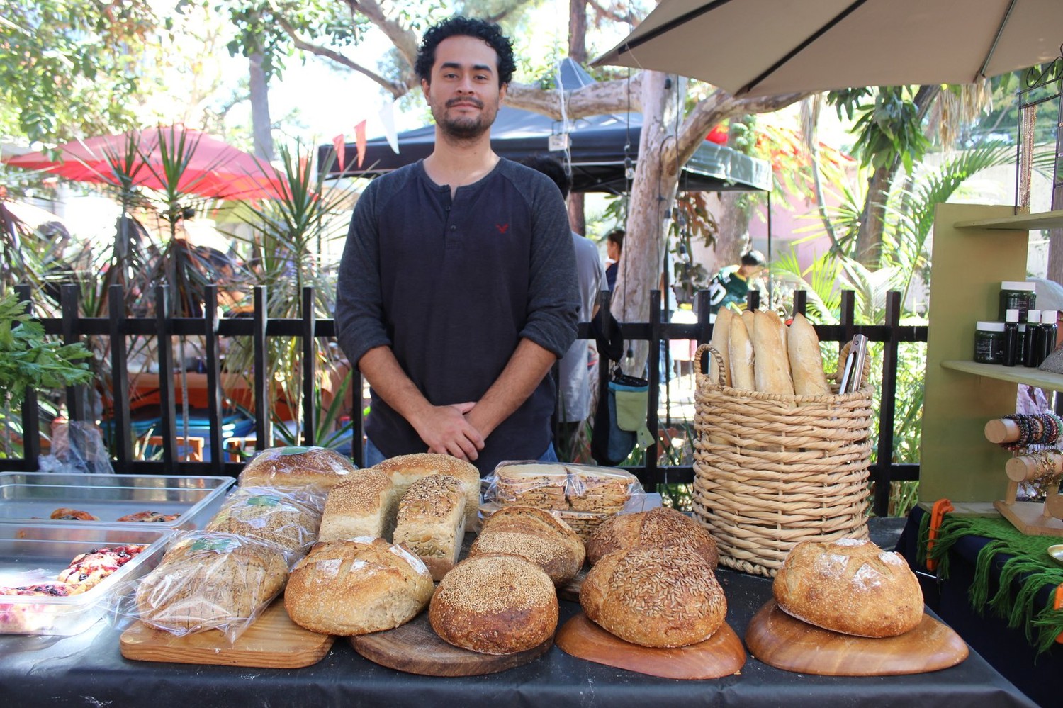 Panadero de Lúcuma detrás de su mesa de panes de masa madre y baguettes, bajo una sombrilla en la Feria