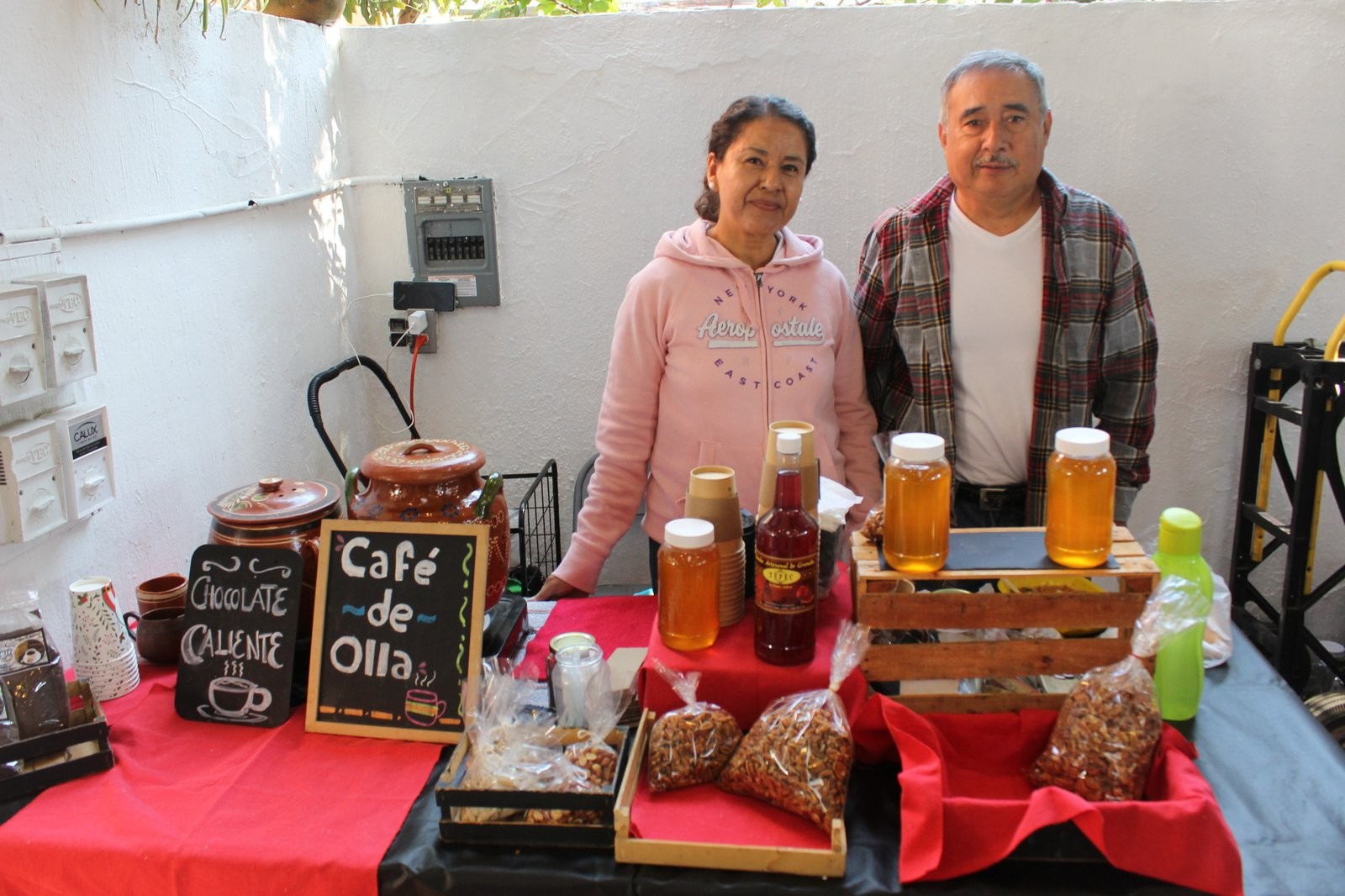 Los dos productores de Maricaro Café y Nuez en su puesto, junto a ollas de barro y letreros de pizarrón de café de olla y chocolate caliente