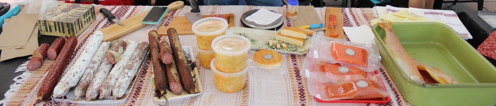 Salamis, quesos y salmón ahumado de Delislav exhibidos sobre la mesa de su puesto