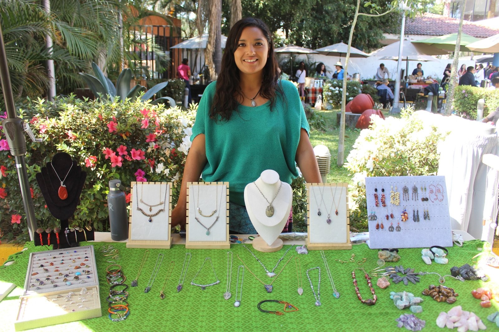 Arianna Cárdenas en el puesto de Yolteótl Joyería, con collares, aretes y piedras exhibidos sobre un mantel verde